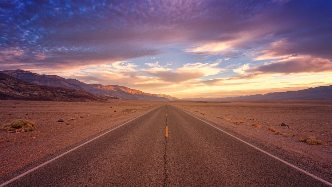 Long desert highway leading toward distant mountains beneath an open sky