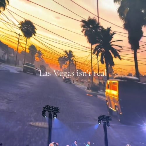 A concert crowd beneath a Las Vegas sunset projection and bright stage lights