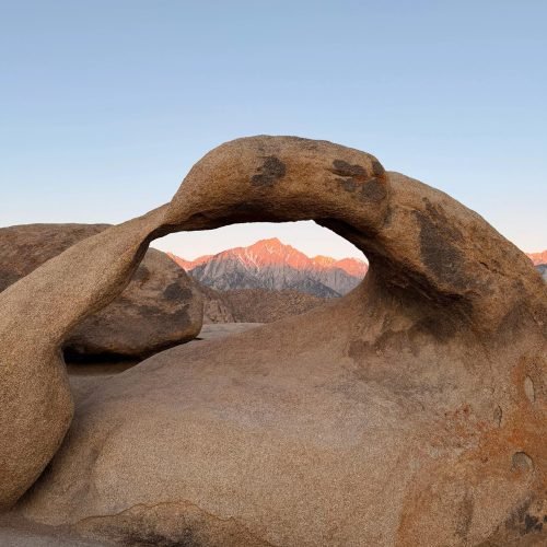 Mobius Arch framing sunlit Sierra Nevada peaks in the Alabama Hills, California