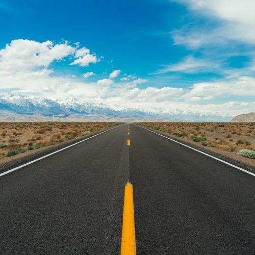 Empty highway crossing a wide desert landscape on a solo road trip