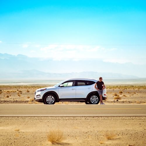 Solo traveller standing beside a four-wheel drive on an open road