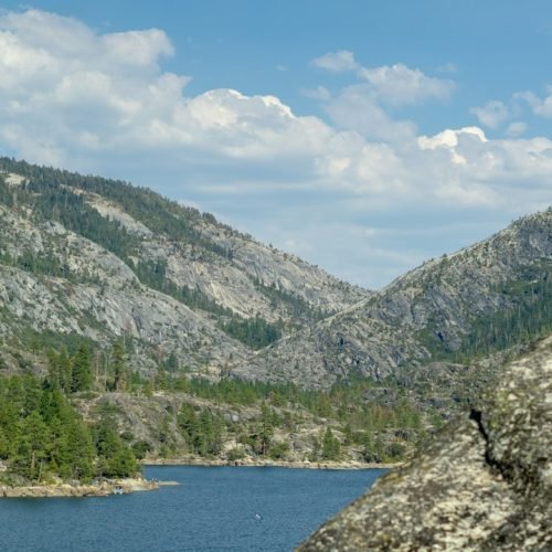 A clear river winding through a forested Yosemite valley beneath granite mountains